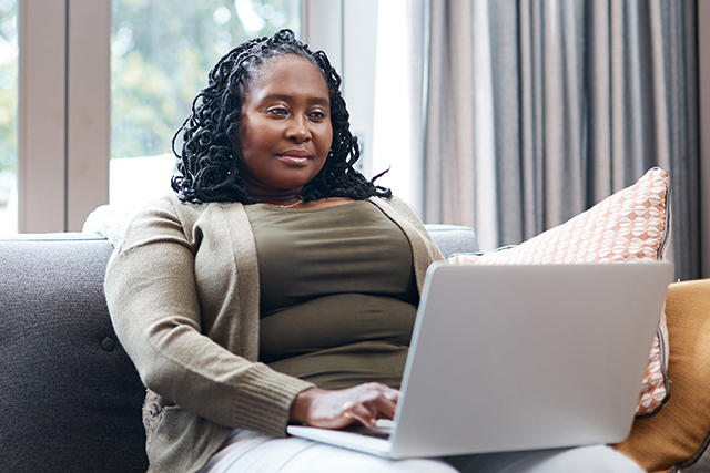 Woman sitting on couch looks at laptop computer screen