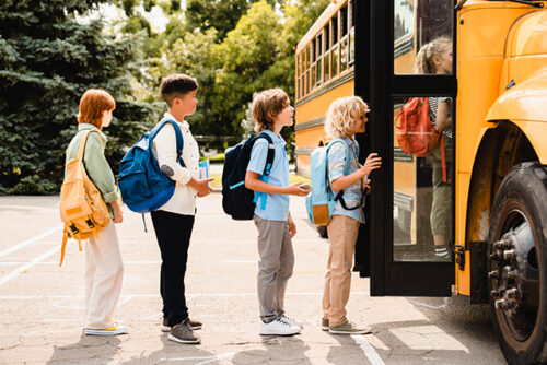 A line of young students waiting to board the school bus