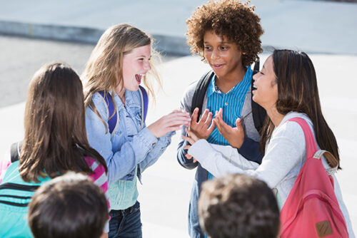 Circle of kids talk and laugh outside