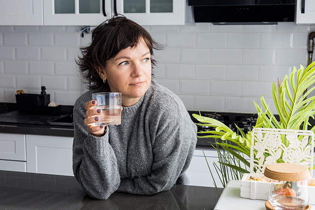 woman standing in kitchen holding a glass of water