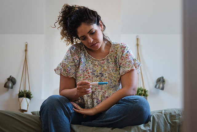 women looks at pregnancy test
