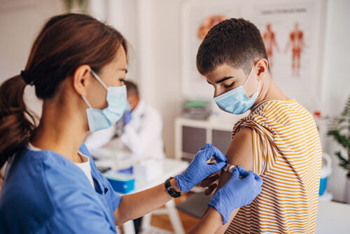 Medical provider gives a boy a shot in his arm at a healthcare facility.