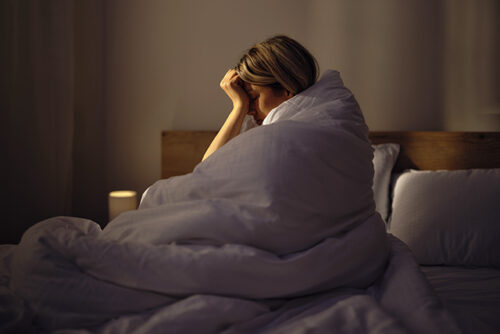 Women in bed in leaning head against hand in discomfort