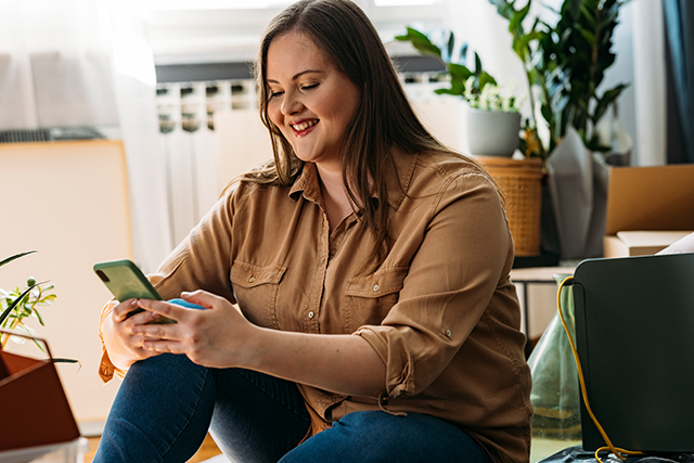 woman smiles as she looks at her smartphone