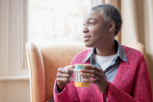 Woman drinking a cup of tea looks off camera, out the window