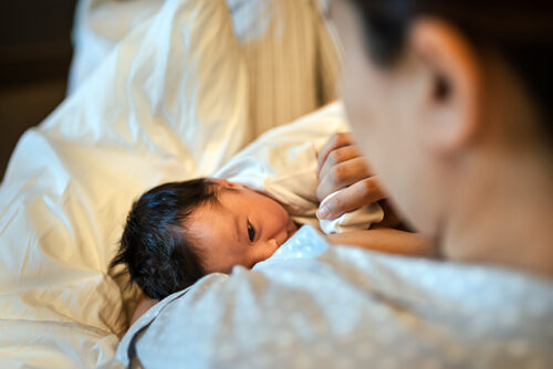 view from over a woman's shoulder as her baby nurses