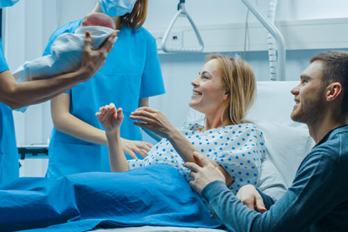 Woman and man are handed their baby after a C-section
