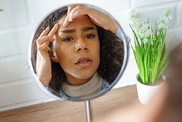 Woman inspects skin in mirror