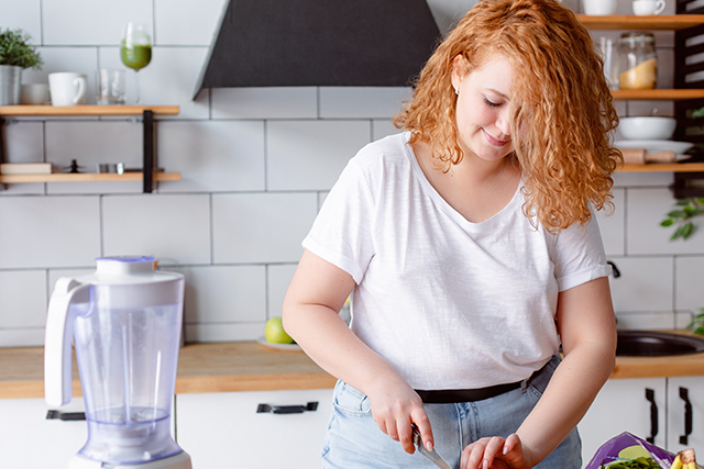Woman stands in the kitchen preparing some food