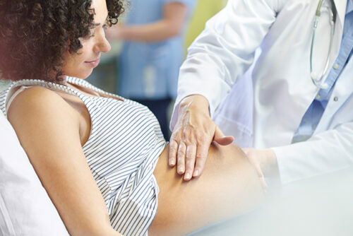 Pregnant woman has her stomach felt by a provider