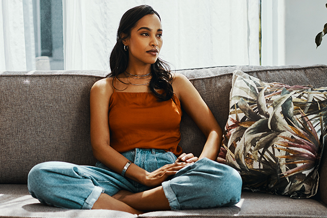 Woman sits on a couch with her legs crossed