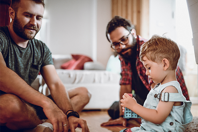 two men play with their son on the floor