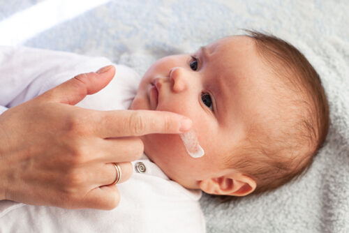 A person out of view applies moisturizer a baby's cheek