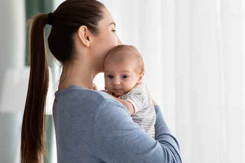Woman holds her baby and looks away from the camera