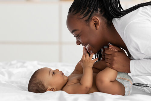 woman leans over her baby and smiles