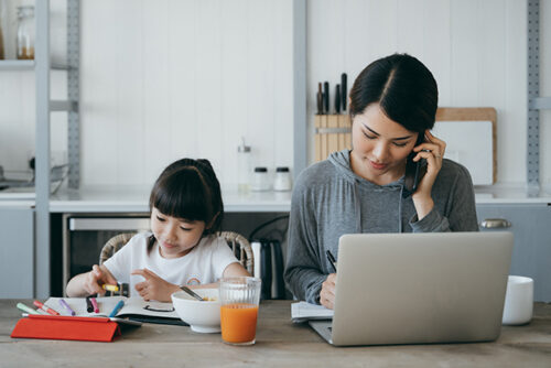 woman on computer works at desk with her child