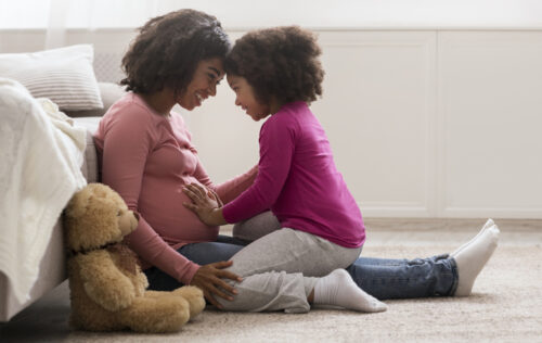 Waiting For Second Baby. Side View Portrait Of Happy Pregnant Black Woman And Her Little Daughter Bonding Together At Home, Copy Space