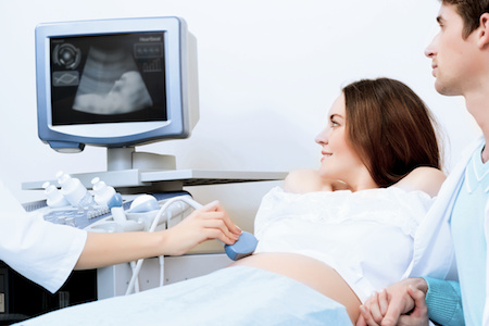 couple in OBGYN office looking at ultrasound of baby