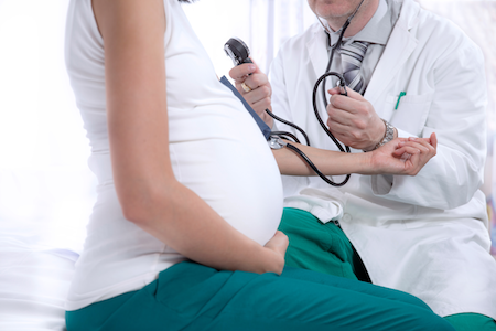 doctor testing pregnant woman for preeclampsia with stethoscope