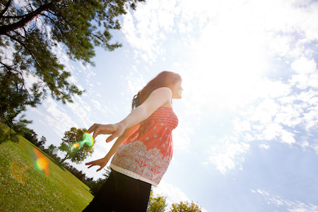 pregnant woman in bohemian top spinning in a field smiling