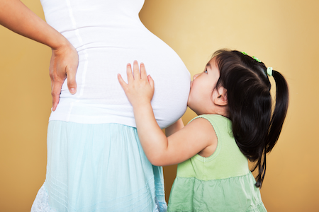 asian girl toddler kissing her mom's pregnant belly