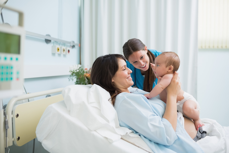 woman lying in delivery room bed with newbon baby
