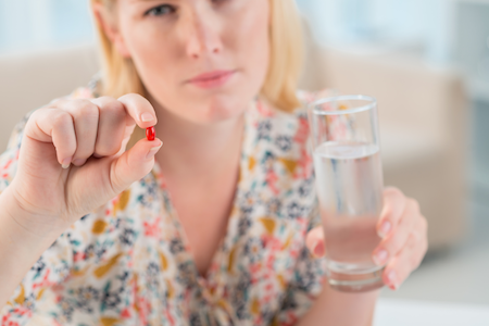 woman holding pill and a glass of water