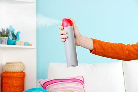 woman spraying odor-neutralizer in living room