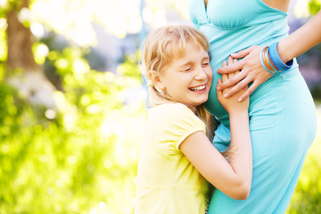 daughter puts her ear to pregnant mother to count baby's kicks