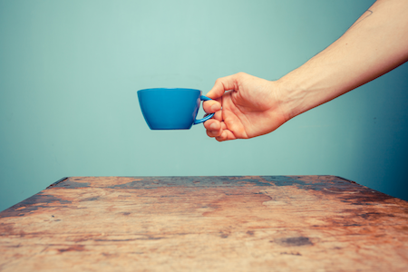 hand holding blue coffee cup over wood table