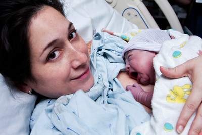 woman lying in hospital bed with her newborn