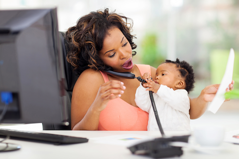 woman talking on the phone at her desk with baby in her lap