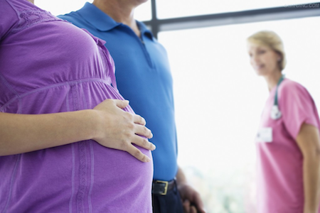 pregnant woman with her hand on stomach walking into hospital