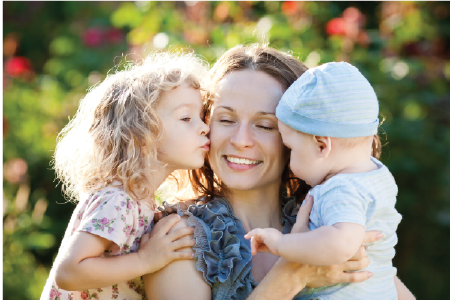 A pregnant woman holding her stomach with her two children.
