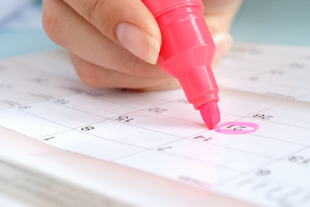 Person circling a day on the calendar with a pink marker to represent how to track your period.