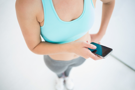 woman in a sports bra holding a mobile phone