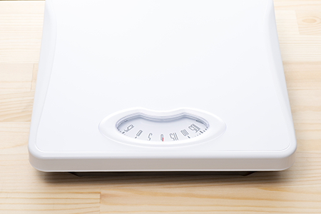 A bathroom scale on the floor to indicate how being overweight may impact fertility.
