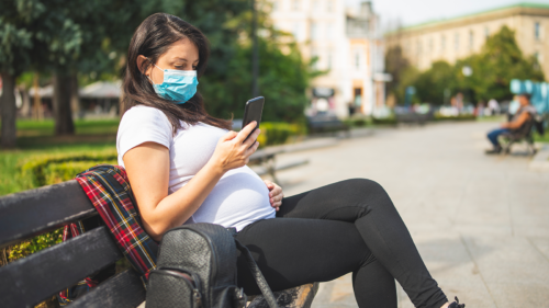 An image of a woman researching pregnancy and COVID on her phone